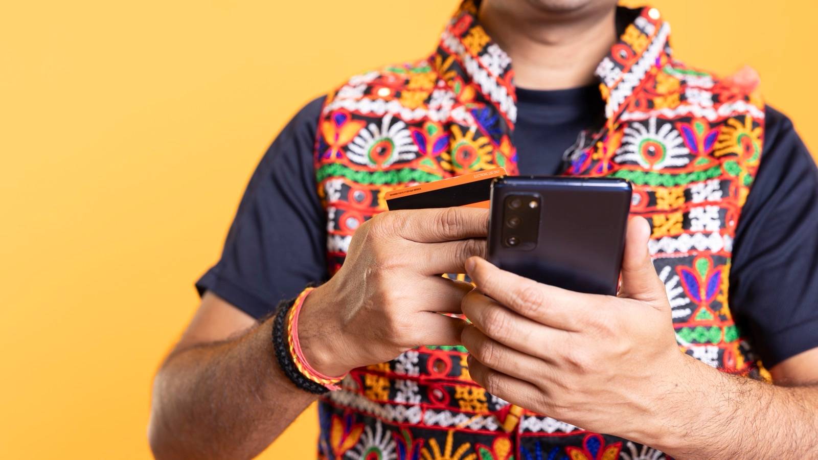 Hands holding a phone and a card while shopping online