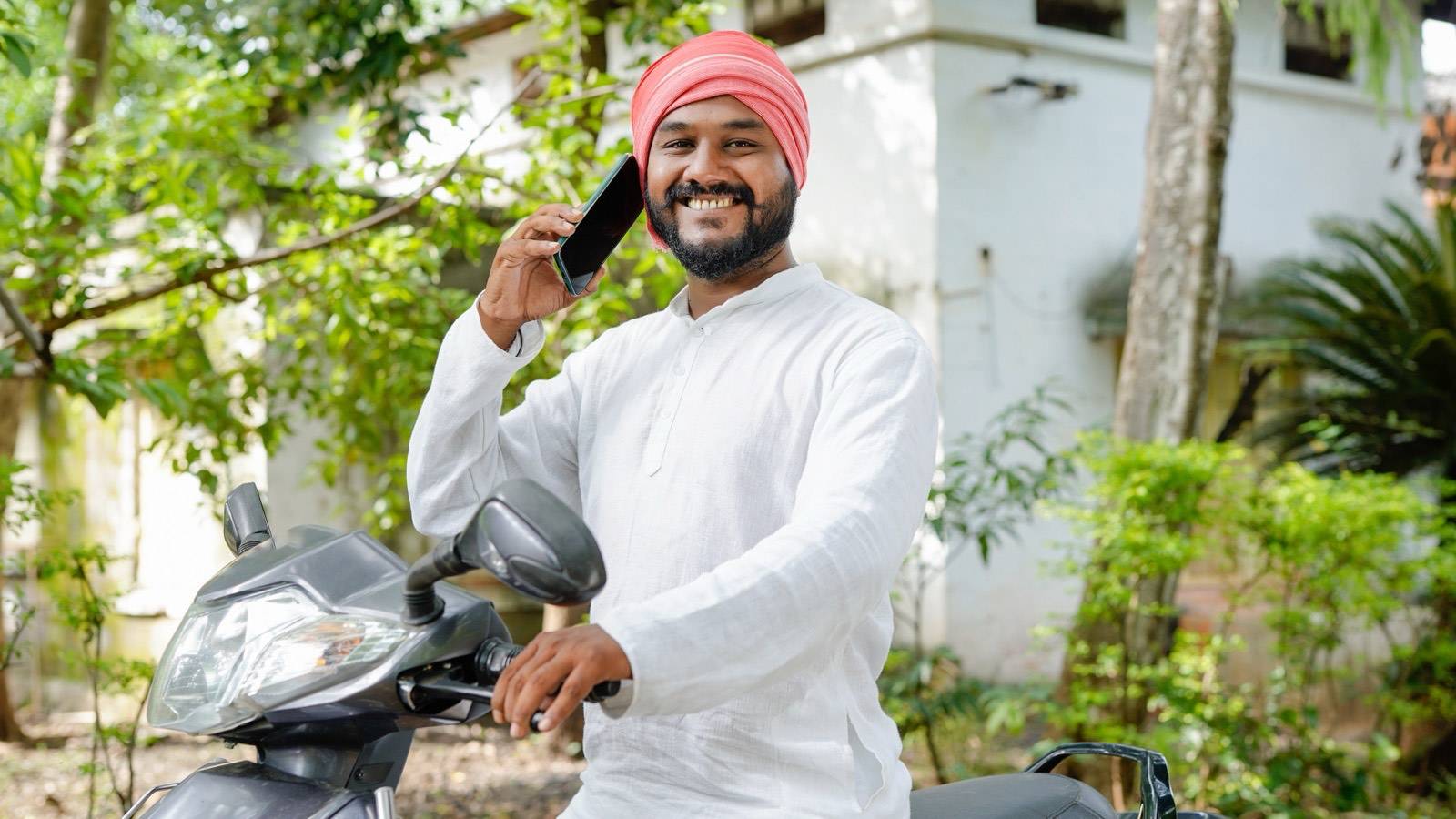 Man on his scooter talking on his phone outside a house
